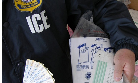  An ICE officer holds fake test scores and ID cards after a bust on a fake student visa ring in 2010.