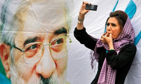 An Iranian protester films an election rally in Tehran on her smart phone. 