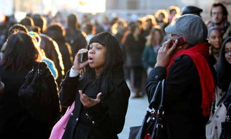 Commuters talk on their phones while waiting in a line to board buses into Manhattan in the wake of Hurricane Sandy.