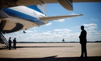 A Secret Service agent stands at right underneath the wing of Air Force One.
