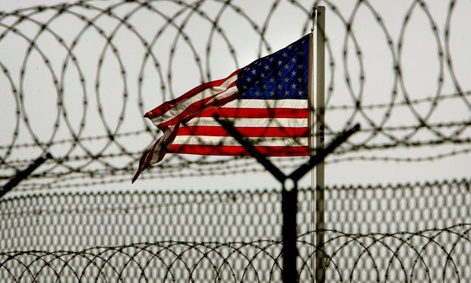 An American flag waves behind the razor-wire fences within the Camp Delta military-run prison at Guantanamo Bay.