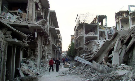Syrian citizens walk in a destroyed street that was attacked on Wednesday by Syrian forces warplanes.