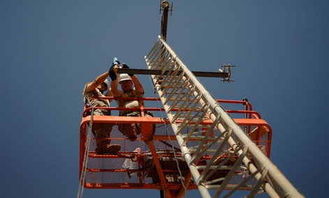 An Army technician attaches a high frequency radio antenna to a communications tower in 2008.