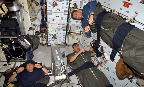 Astronauts Pam Melroy, George Zamka, bottom right,and European Space Agency's Paolo Nespoli, sleep in their sleeping bags, which are secured on the middeck of the Space Shuttle Discovery while docked with the International Space Station.