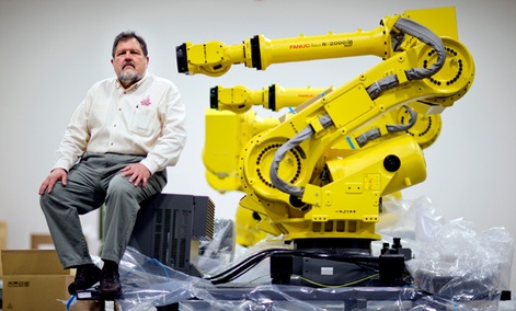 Rosser Pryor, Co-owner and President of Factory Automation Systems, sits next to a new high-performance industrial robot at the company's Atlanta facility.