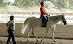 Marine Corps veteran Angel Gomez rides a horse as an instructor looks on during Hippotherapy at the NCEFT, National Center for Equine Facilitate Therapy.