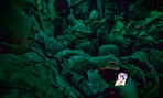 Staff Sgt. Rulberto Qjendismiranda with the U.S. Army's 2nd Battalion 27th Infantry Regiment looks at his mobile phone while aboard a military transport flight.