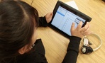A young girl in a special education classroom reads a worksheet on an iPad in 2011.