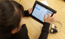 A young girl in a special education classroom reads a worksheet on an iPad in 2011.