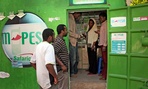 Customers make money transfers at an M-Pesa counter in Nairobi, Kenya. A mobile banking service, M-Pesa allows people without a bank account to transfer money between phones instantly. Customers make money transfers at an M-Pesa counter in Nairobi, Kenya. A mobile banking service, M-Pesa allows people without a bank account to transfer money between phones instantly.