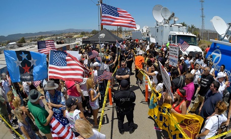 Demonstrators from opposing sides confront each other while being separated by Murrieta police officers, July 4, 2014, outside a U.S. Border Patrol station in Murrieta, Calif. Demonstrators from opposing sides confront each other while being separated by Murrieta police officers, July 4, 2014, outside a U.S. Border Patrol station in Murrieta, Calif.