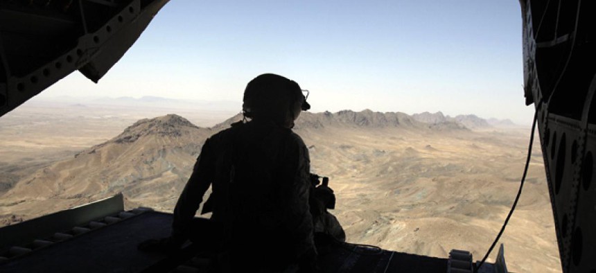 A U.S. helicopter tail gunner looks out over mountains in Afghanistan.
