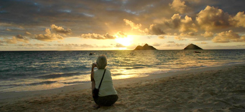 A tourist watches the sunrise near Hawaii's Lanikai Beach.