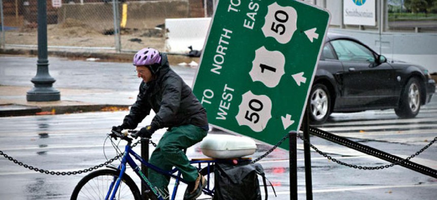 A cyclist rides by a downed traffic sign and the Smithsonian National Museum of African American History and Culture in Washington Tuesday after the storm.