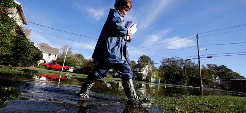Letter carrier Dawn Greco wades in the water to deliver the mail after superstorm Sandy.