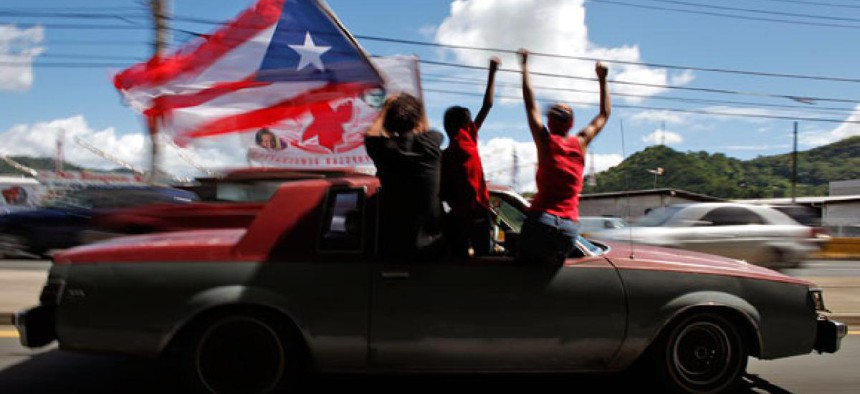 People ride atop a vehicle waving a Puerto Rican flag during elections in San Juan, Puerto Rico, Tuesday, Nov. 6, 2012. 
