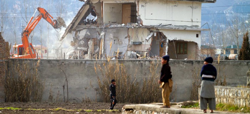 A police commando stands guard as authorities use heavy machinery to demolish Osama bin Laden's compound in Abbottabad, Pakistan.