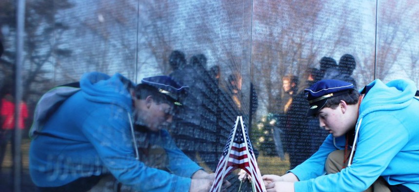 Bruce Wolff, 14, of Canton, Ohio, kneels for a closer look at items left at the Vietnam Veterans Memorial wall. More than 400,000 items have been left since the wall opened in 1982.