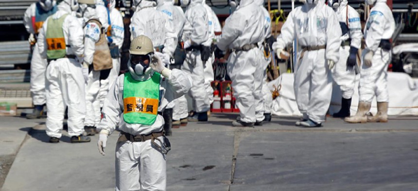 A group of workers wearing protective suits and masks stand next to the No. 4 reactor at Tokyo Electric Power Co. (TEPCO)'s tsunami-crippled Fukushima Dai-ichi nuclear power plant.