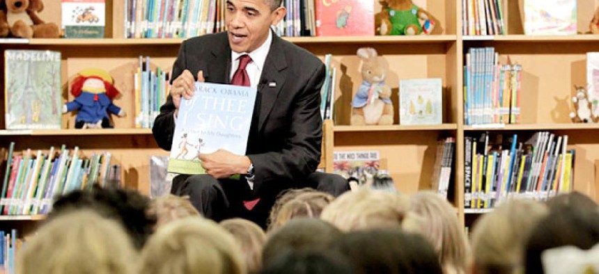 President Barack Obama holds up a book he authored, 'Of Thee I Sing: A Letter to My Daughters', before reading to students at Long Branch Elementary in Arlington, Va. 