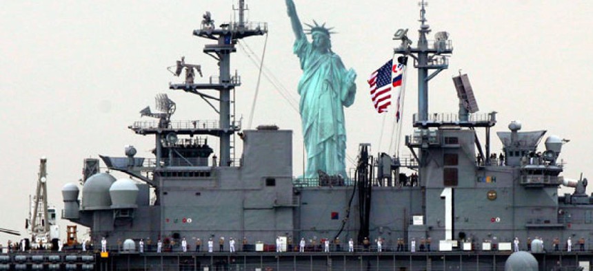 Sailors line the deck of the USS Wasp as she sails by the Statue Of Liberty, in New York, to participate in 2012 Fleet Week activities,