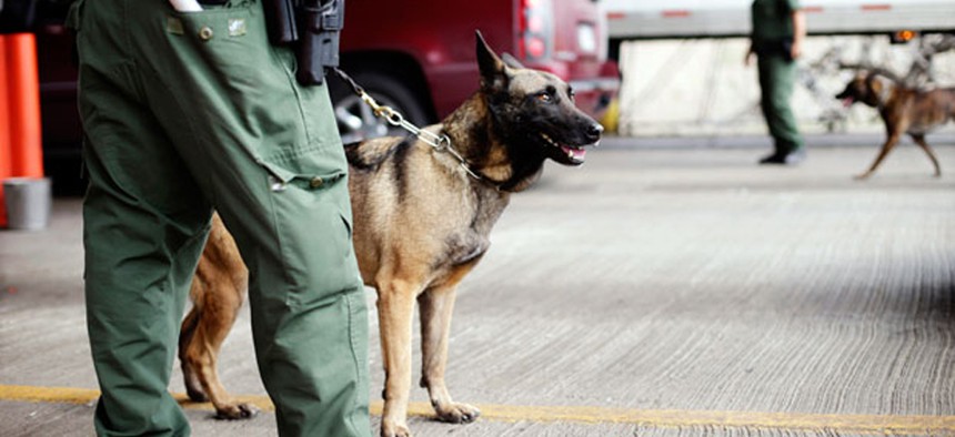 U.S. Customs and Border Protection agents and K-9 security dogs keep watch at a checkpoint station, on Feb. 22, 2013, in Falfurrias, Texas.