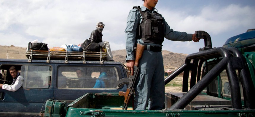 An Afghan police officer stands guard at a checkpoint on a road leading to Narkh district on the outskirts of Maidan Shahr, Afghanistan