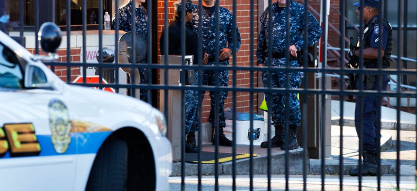 Naval officers  stand guard inside the gate of the closed Navy Yard Tuesday.