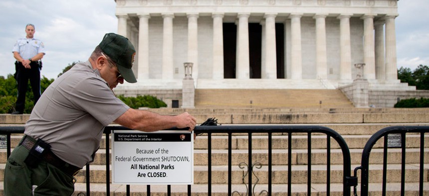 A Park Police officer watches as a National Park Service employee posts a sign on a barricade closing access to the Lincoln Memorial on Oct. 1, the day the government shutdown began.