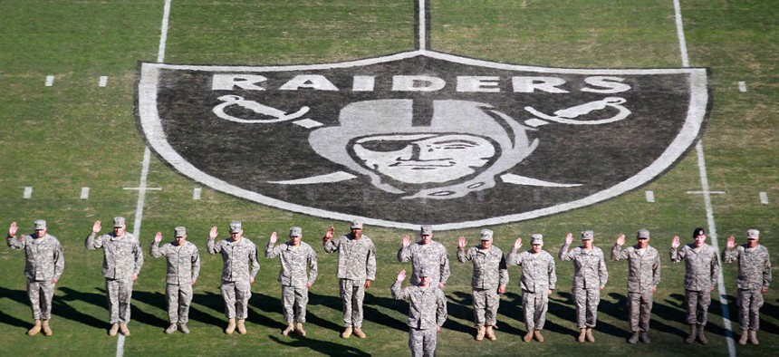 Servicemembers stand on the field before the game at the Oakland Coliseum Sunday.