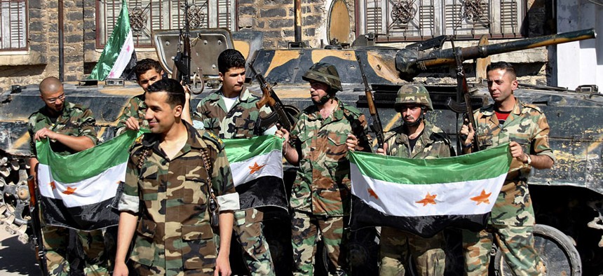 Syrian army soldiers hold the Syrian revolution flags in 2012.