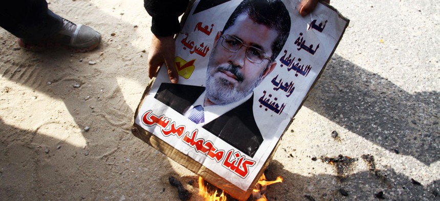 An opponent of Egypt's ousted President Mohammed Morsi burns a poster with his photo on it in Cairo, Egypt, Wednesday, Jan. 8, 2014.