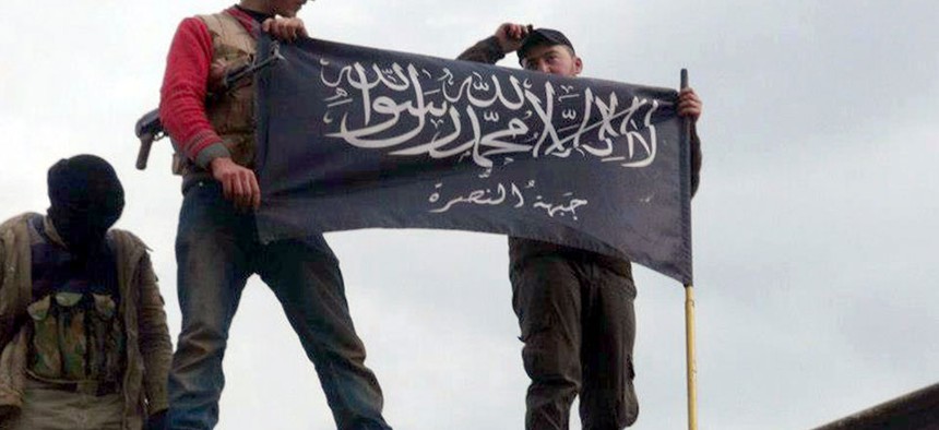 Rebels from al-Qaida affiliated Jabhat al-Nusra waving their brigade flag as they step on the top of a Syrian air force helicopter.