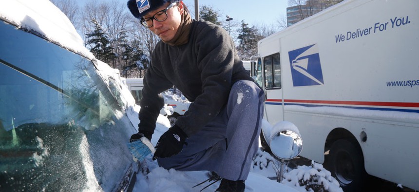 Danny Kim clears snow and ice as he climbs on the hood of his mail delivery truck in January.