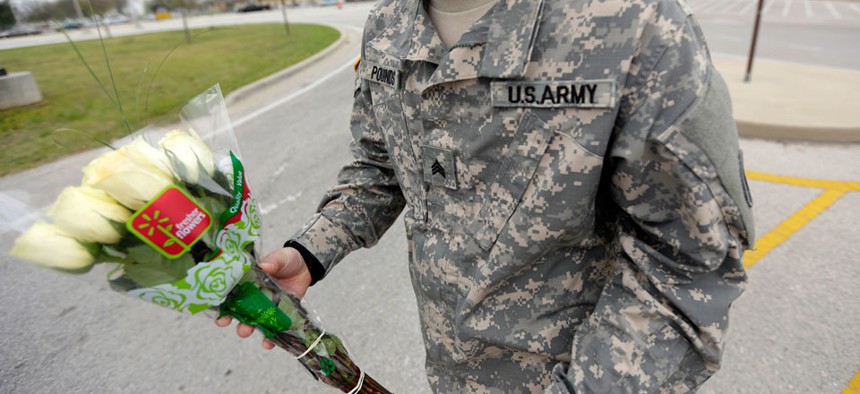 An unidentified soldier holds flowers dropped off at Fort Hood's main gate for shooting victims, Thursday, April 3, 2014.