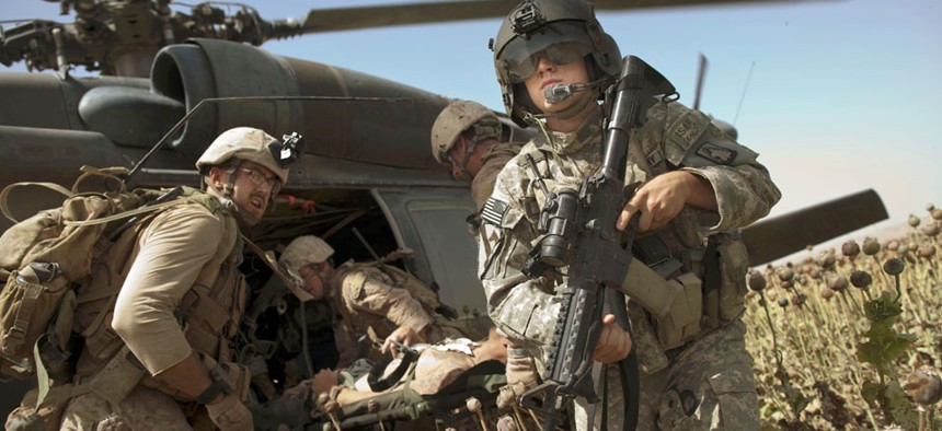US Army flight medic SPC. Daniel Miller, right, stands guard as United States Marines place a colleague wounded in an IED strike into a waiting U.S. Army medevac helicopter. 