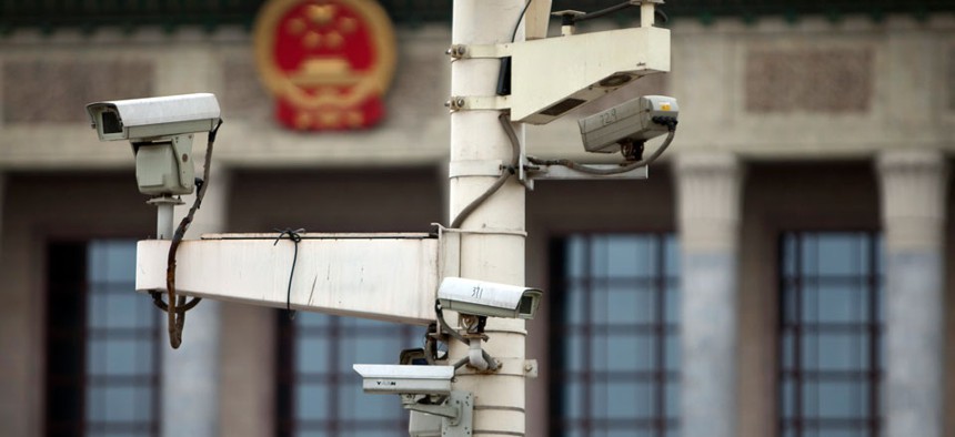 Surveillance cameras are set up at a lamp post against a China national emblem at Tiananmen Square in Beijing, China.