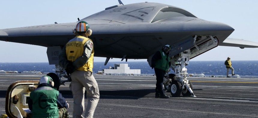Flight deck crew prepare to launch the Navy experimental unmanned aircraft, the X-47B, aboard the nuclear powered aircraft carrier USS Theodore Rosevelt.