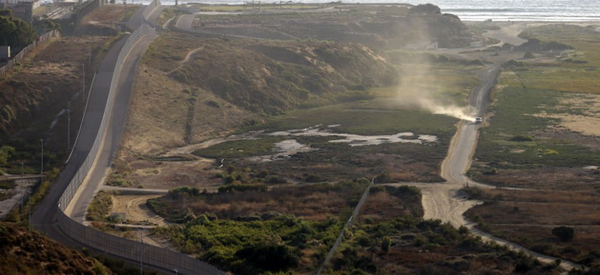 A U.S. Border Patrol vehicle, right, drives along a road running alongside the border structures that separate Tijuana, Mexico, left, from San Diego.