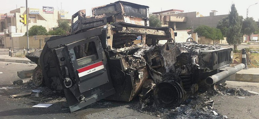An Iraqi army armored vehicle is seen burned on a street of the northern city of Mosul Thursday.