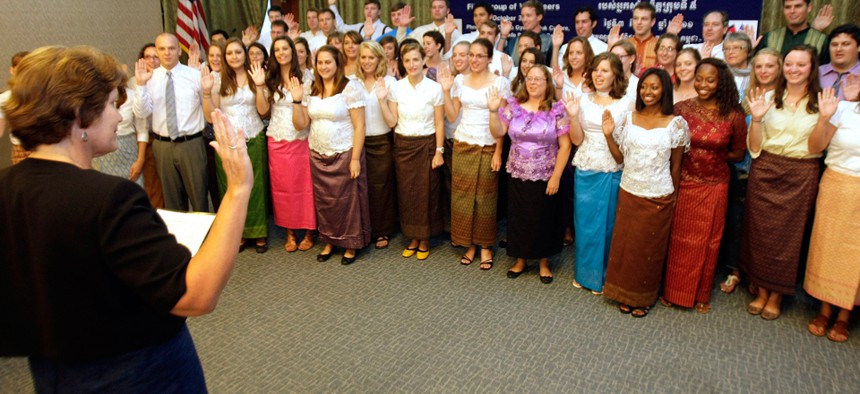 Peace Corps volunteers raise their hands to swear in during a ceremony in Phnom Penh, Cambodia in 2011.