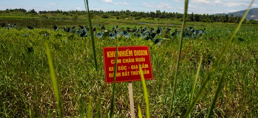 A warning sign stands in a field contaminated with dioxin from Agent Orange near Danang airport.