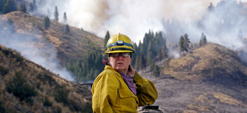 Firefighter Kathleen Calvin sits atop her fire truck as smoke from a wildfire fills the sky in Winthrop, Washington.