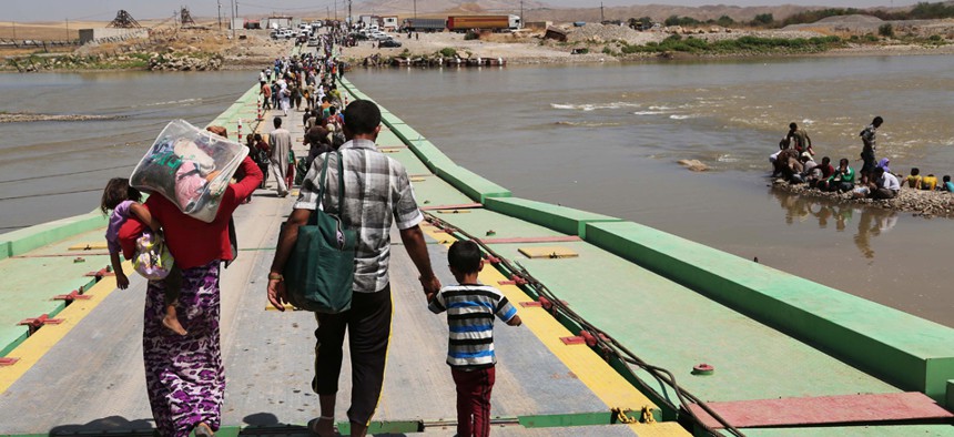 Displaced Iraqis from the Yazidi community cross the Iraq-Syria border at Feeshkhabour bridge over Tigris River Sunday.