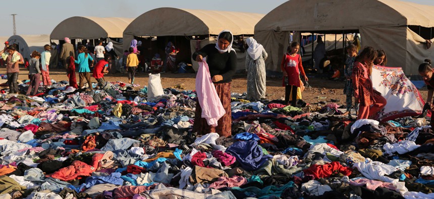 Displaced Iraqis from the Yazidi community look for clothes to wear among items provided by a charity organization at the Nowruz camp in Syria.