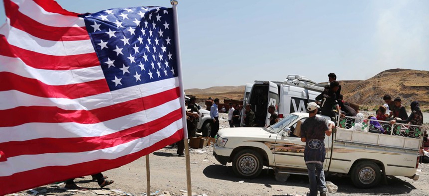 A U.S. flag waves while displaced Iraqis from the Yazidi community cross the Syria-Iraq border on Feeshkhabour bridge Sunday.