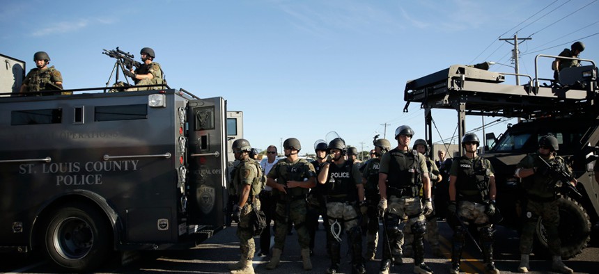 Police in Ferguson clad in SWAT gear watch protestors Wednesday.