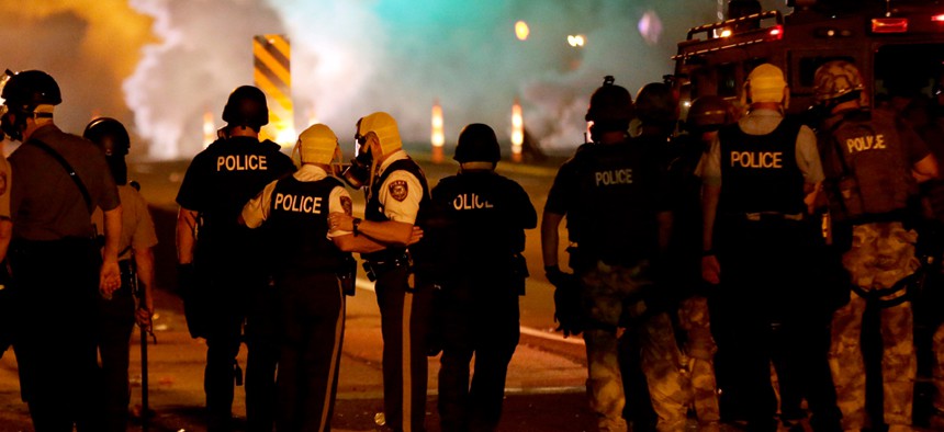 Police talk after deploying tear gas Sunday evening in Ferguson, Missouri.