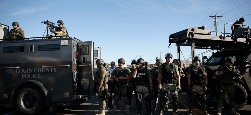 Police in Ferguson clad in SWAT gear watch protestors Aug. 9.
