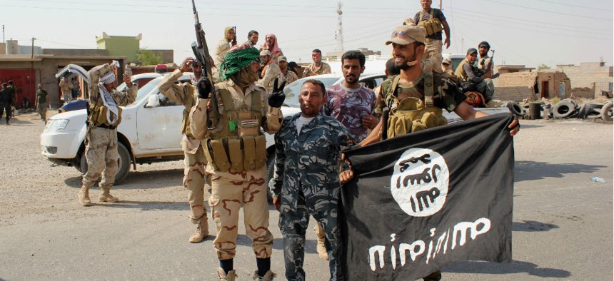Shiite militiamen north of Baghdad, Iraq, hold the flag of the Islamic State group they captured. 